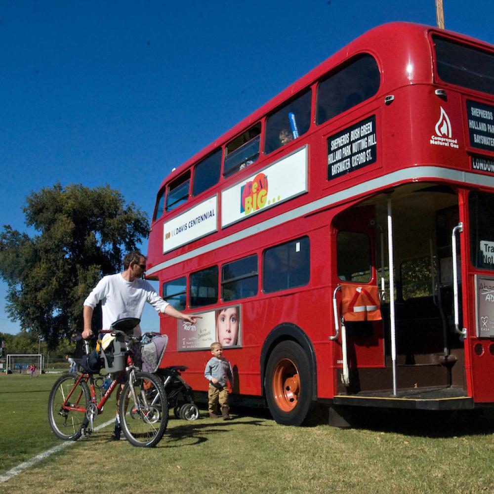 parent and their child next to a bus with a bicycle