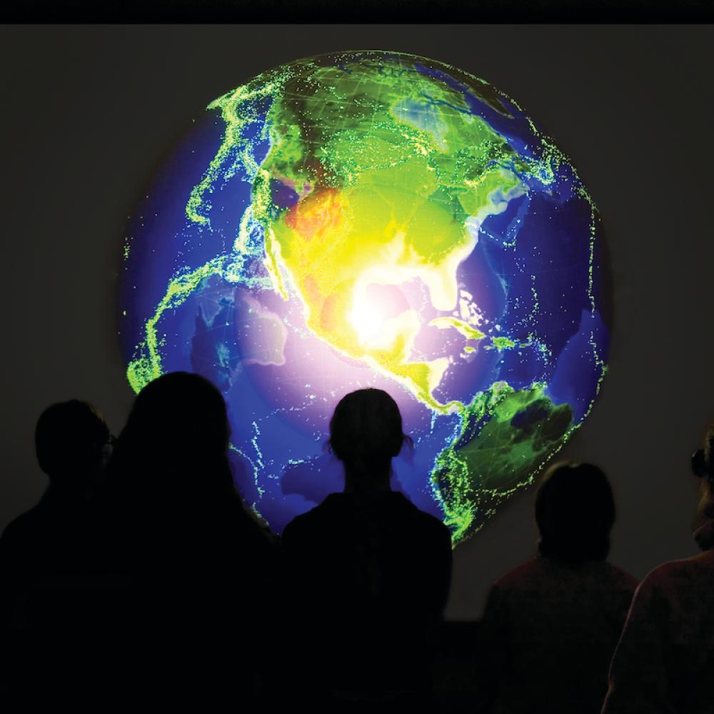 people looking at a visualization of earth